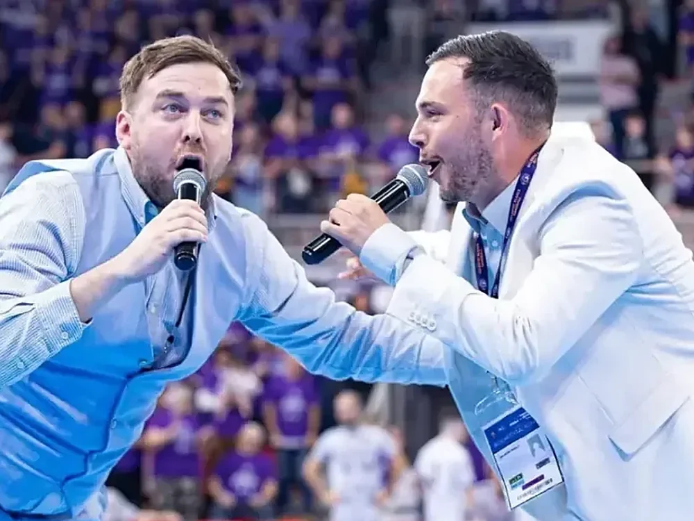 Deux speakers au micro face aux tribunes d'un match de handball